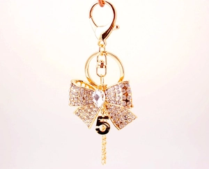 Détail du porte-clés doré en strass avec nœud papillon et pendentif numéro cinq