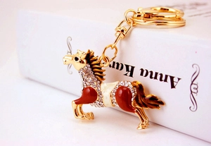 Close-up of golden horse keychain with white rhinestones and brown enamel details