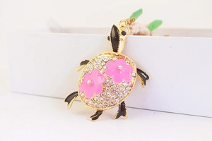 Détail du porte-clés tortue en métal doré avec strass et fleurs en émail rose