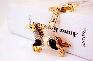 Close-up of golden horse keychain with sparkling rhinestones and black enamel detail