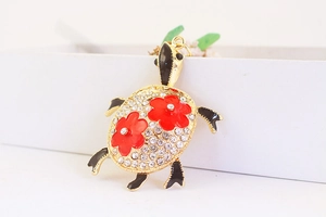 Vue détaillée du porte-clés tortue avec strass scintillants et fleurs en émail rouge