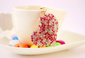 Dettaglio di un portachiavi a cuore con strass colorati su una tazza in ceramica