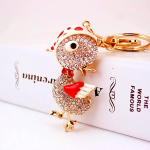 Porte-clés canard en strass avec chapeau à pois et ailes rouges sur un livre