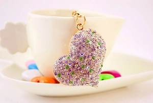 Dettaglio del portachiavi a cuore con strass viola appeso a una tazza di ceramica