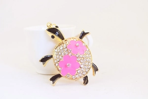 Gros plan d'un porte-clés tortue en strass avec fleurs roses et métal doré poli