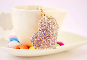 Dettaglio di un ciondolo a cuore con strass AB appeso a una tazza di ceramica bianca