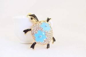 Détail du porte-clés tortue avec strass brillants et fleurs bleues sur métal
