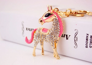 Close-up of golden horse keychain with white rhinestones and pink enamel details