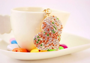 Dettaglio di un ciondolo a cuore dorato con strass colorati su una tazza di ceramica