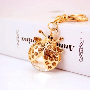 Porte-clés coccinelle chic avec strass ambrés et cristal facetté sur métal doré élégant