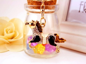 Close-up of golden horse keychain with white crystals and black enamel details