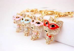 Vue détaillée de porte-clés cochons dorés avec strass et masques colorés