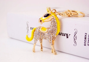 Close-up of golden horse keychain featuring sparkling white crystals and yellow enamel