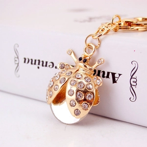Porte-clés coccinelle mignon avec strass scintillants et placage or sur un livre blanc