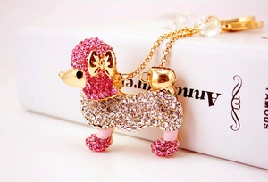 Détail d'un porte-clés caniche en cristal rose avec nœud doré et strass sur livre