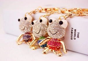 Vue macro de trois porte-clés grenouille en cristal de couleurs violette, sarcelle et rose