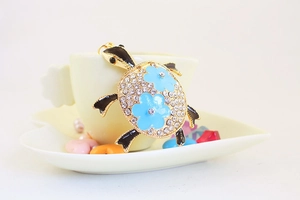 Détails du porte-clés tortue avec cristaux blancs et fleurs en émail bleu