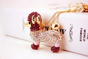Détail du porte-clés caniche en cristal avec strass violets et nœud doré élégant