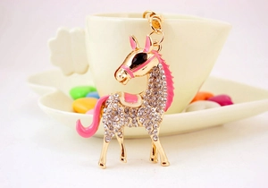Close-up of golden horse keychain featuring pink enamel details and sparkling rhinestones