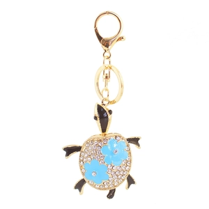 Porte-clés tortue dorée avec strass blancs et petits accents de fleurs bleues