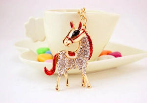 Close-up of golden horse keychain with sparkling rhinestones and red enamel details