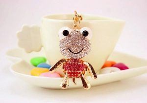 Détail d'un joli porte-clés grenouille avec strass roses et blancs sur une tasse