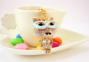 Détail d'un porte-clés cochon en strass avec lunettes bleues sur une tasse blanche