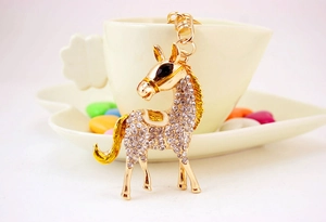 Close-up of golden horse keychain with sparkling rhinestones hanging on a white coffee cup