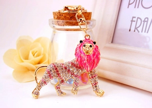 Detail of a lion keychain with pink rhinestones and gold alloy on a decorative background