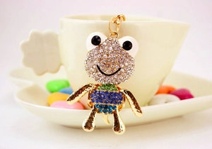 Détail d'un porte-clés grenouille strass suspendu à une tasse avec bonbons colorés