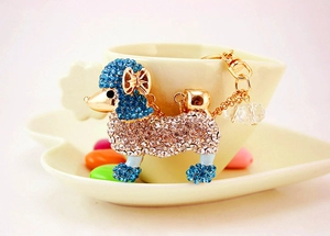 Détail d'un porte-clés caniche en cristal avec strass bleus et blancs sur base dorée