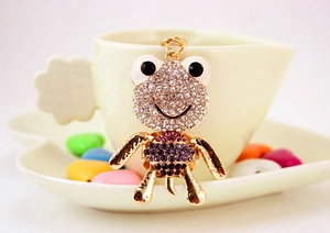 Détail d'un porte-clés grenouille en strass brillant sur une tasse à café blanche