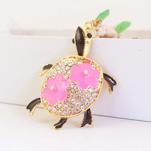 Porte-clés tortue en cristal avec fleurs en émail rose sur une base en métal doré