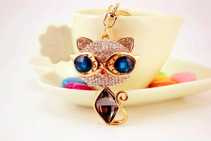 Dettaglio portachiavi a gatto con occhi in cristallo blu e strass su tazza
