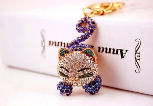 Détail d'un porte-clés chat mignon avec strass bleus et blancs sur métal doré