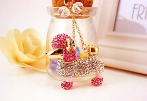 Détail du porte-clés caniche en cristal avec strass roses sur fond de fleurs douces