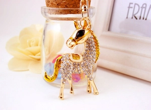 Detail of a crystal-encrusted gold horse keychain with yellow enamel accents and lobster clasp