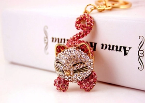 Détail d'un porte-clés chat doré orné de strass brillants blancs et roses scintillants