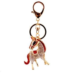 Sparkling crystal horse keychain with golden plating and red enamel details on white background