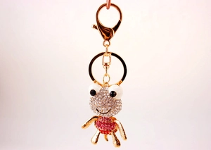 Gros plan du porte-clés grenouille dorée avec strass blancs et roses et fermoir