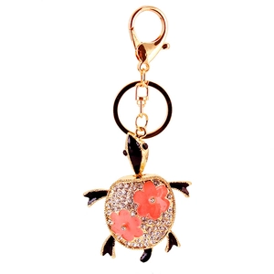 Porte-clés tortue dorée avec strass blancs et motifs floraux roses sur fond blanc