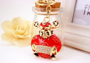 Detail of a red God of Wealth keychain with white rhinestones and a gold-plated spring clasp