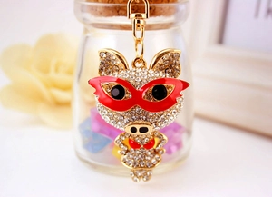 Détail du porte-clés cochon en strass étincelants avec masque en émail rouge et mousqueton