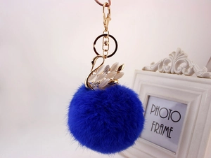 Dettaglio del ciondolo a cigno dorato con pompon in pelliccia blu e cristalli lucidi