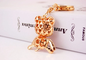 Détail macro du porte-clés ours doré avec motif cœur ajouré et strass scintillants