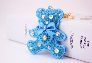 Macro shot of sky blue crystal rhinestone teddy bear pendant with a golden keyring