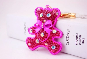 Macro detail of a pink bear keychain decorated with sparkling red rhinestones and a gold ring