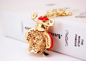 Detail of a gold God of Wealth keychain with red enamel and intricate Ruyi pattern