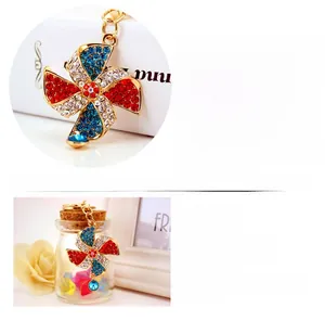 Detail view of rotating windmill keychain with red and blue rhinestones in gold plating
