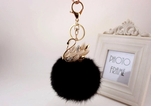 Dettaglio portachiavi pompon nero con cigno dorato e pietra opale per borsa e zaino